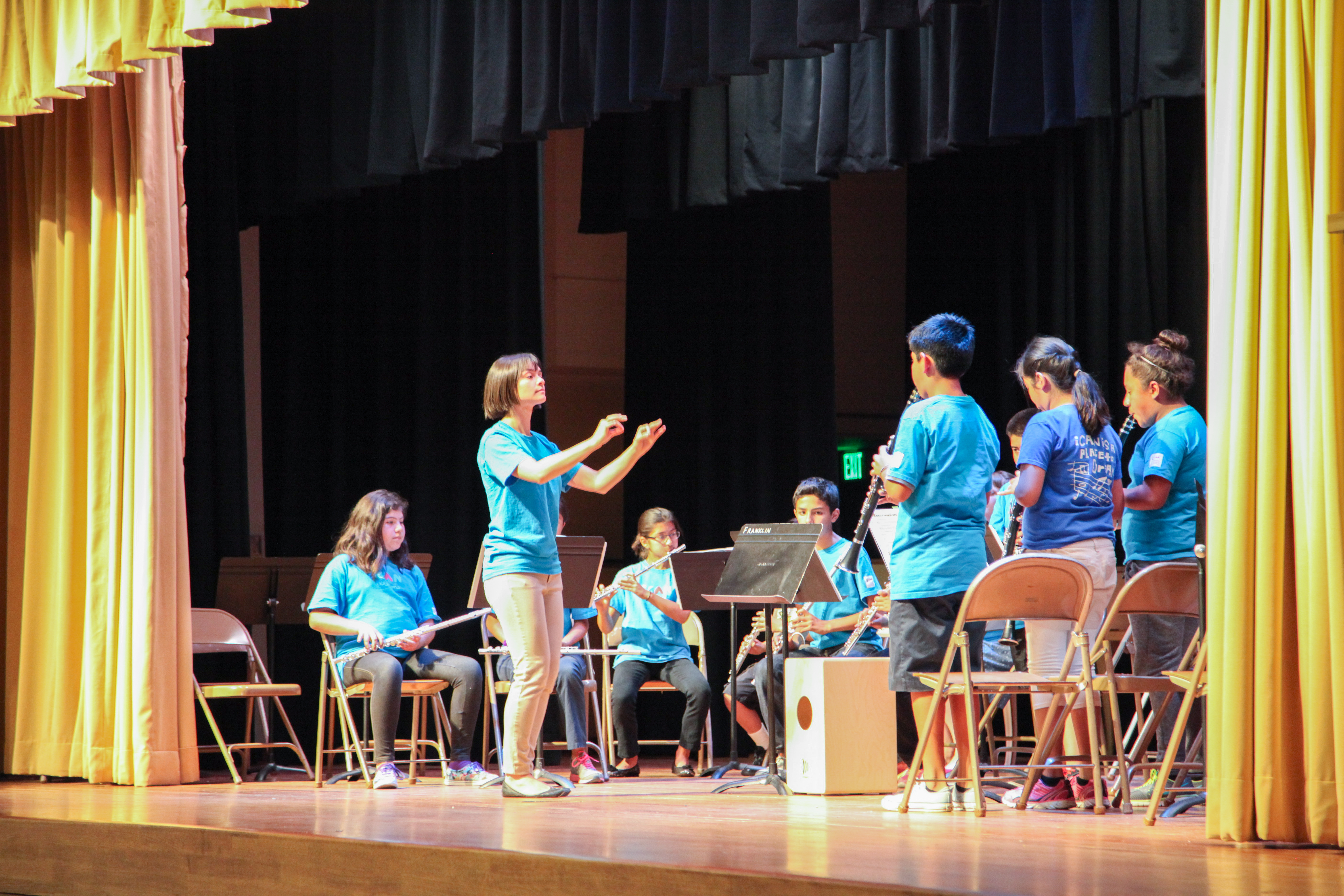 Gabrielle Molina conducting a youth ensemble of young wind players on stage